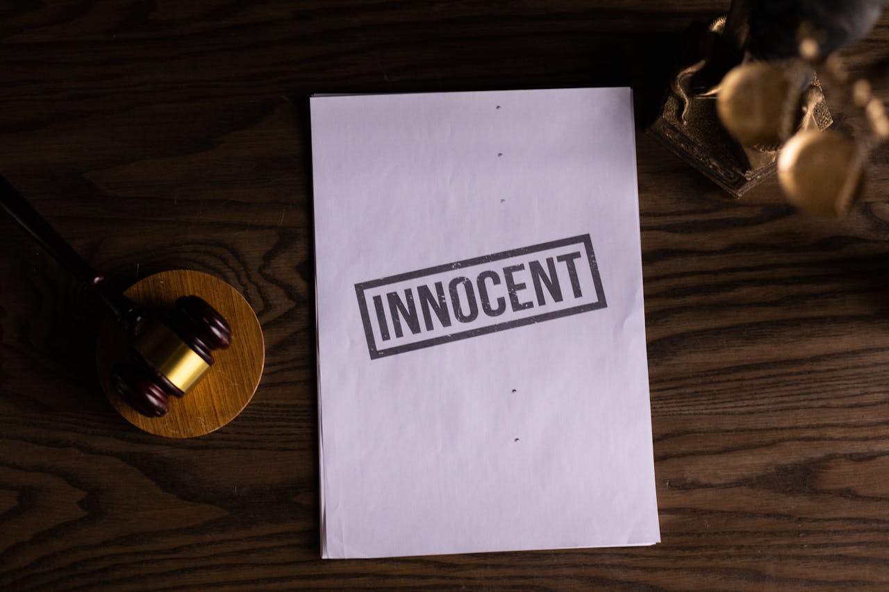 Close-up of legal document stamped 'Innocent' beside a gavel on a wooden desk.