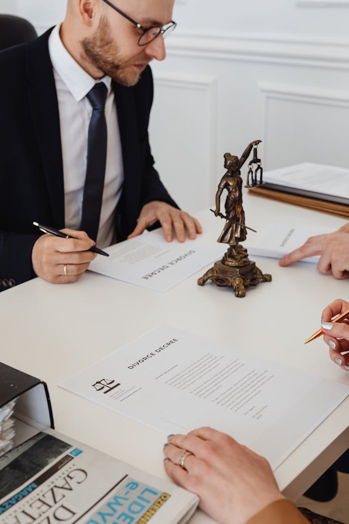 Lawyers reviewing and signing divorce decree documents in a formal office setting.