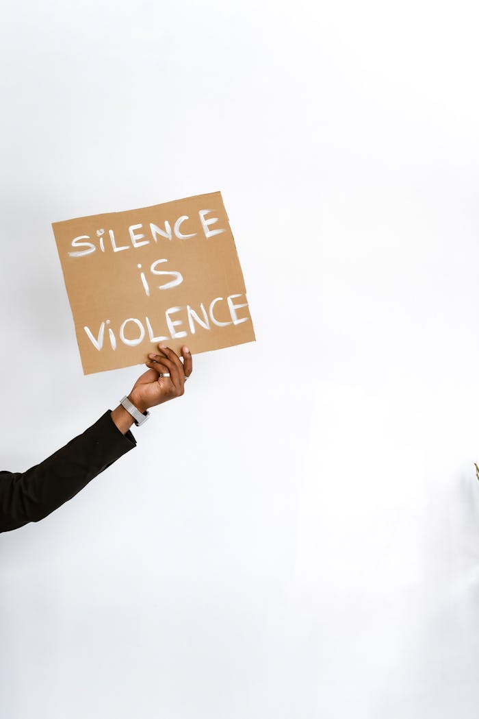 Person holding placard with 'Silence is Violence' message, advocating for change.